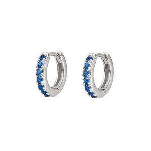 Macro shot of silver huggie earrings with seven round blue zircon stones in claw setting