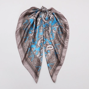 Close-up of intricate paisley patterns on a silk-like square scarf with blue and taupe tones