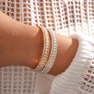 Close-up of luxury multi-layer gold bracelet with white pearls and sparkling rhinestones