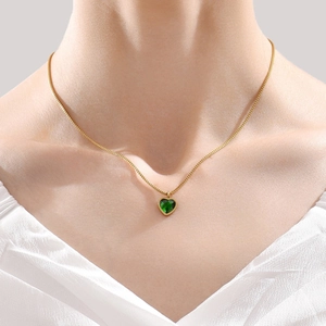 Elegante collar dorado con colgante de corazón de piedra verde usado por una modelo