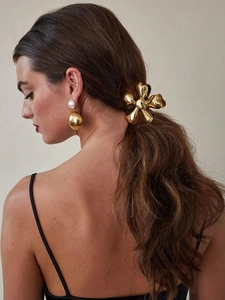 Detail of elegant gold metal flower hair claw and pearl earring set on a model