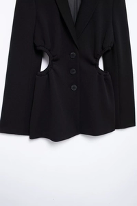 Detailed view of women's black blazer with unique waist cut-out and three-button closure