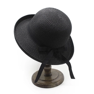 Women's black straw sun hat with ribbon bow and curved brim on display stand