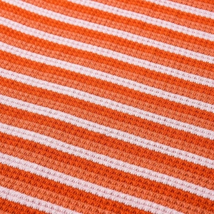 Macro shot of the orange and white striped knit fabric texture on the summer dress