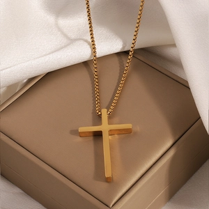 Detail of a minimalist gold cross pendant with high polish finish on elegant white silk