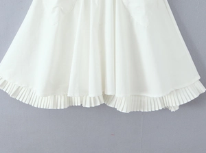 Detail of white pleated dress hemline showing layered ruffles and soft cotton fabric