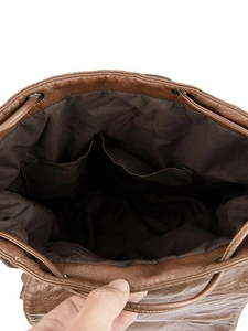 Brown rivet leather backpack main view showing spacious interior with drawstring closure