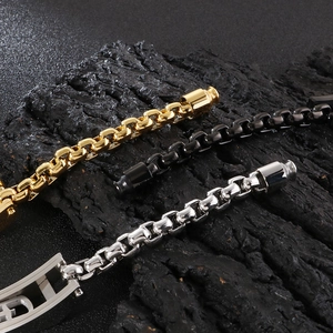 Detailed close-up of 18K gold plated box chains in gold, silver, and black on dark rock