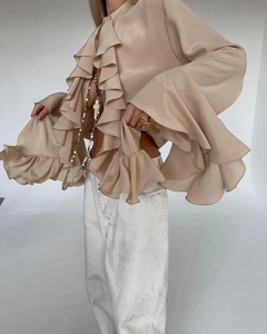 Detailed view of champagne satin shirt with layered ruffles and textured silk fabric