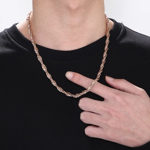 Gros plan d'une chaîne torsadée en or rose portée sur un t-shirt noir pour homme