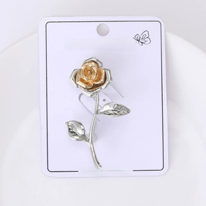 Detailed close-up of a two-tone rose brooch with matte gold petals and silver leaves