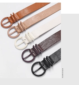 Detail view of five retro faux leather belts with round buckles in various colors