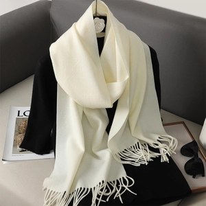 Close-up of soft cream white cashmere-like scarf featuring elegant tassel fringe details
