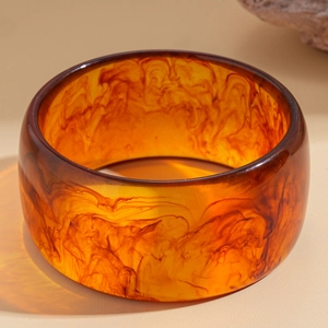 Macro shot of wide resin bangle with amber tint and coffee swirling marble textures