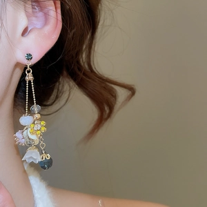 Close-up of elegant gold chain earrings with crystal flowers and grey beads on a model