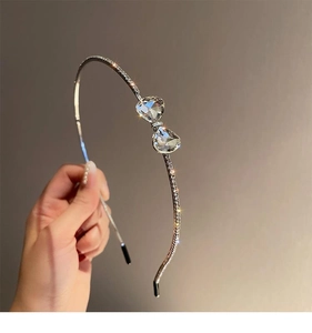 Close-up of a silver headband with a rhinestone bow and clear crystals detail