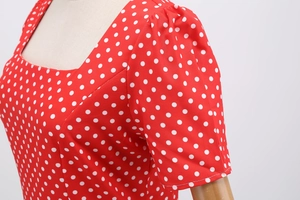 Detail of square neckline and puff sleeves on a red polka dot dress with textile texture