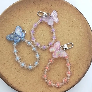 Detailed macro of iridescent butterfly charms with colorful floral beads and lobster clasps