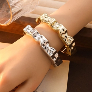 Close-up of irregular wavy metal bracelets in gold and silver finish on a book