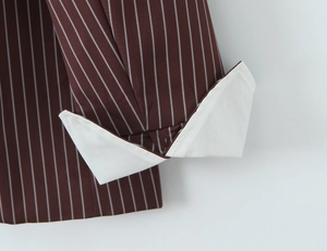 Close-up of dark brown striped blazer cuff with white lining and detailed texture