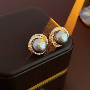 Detailed macro view of gray pearl earrings with sparkling zircon halo on dark leather case