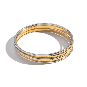 Macro detail of stacked gold and silver stainless steel bangles with textured diagonal patterns