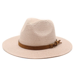 Detail of straw fedora hat featuring woven texture and brown suede band with tassel