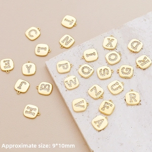 Macro detail of gold-plated 9x10mm square letter pendants with inlaid cubic zirconia