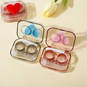 Detail of clear contact lens case kit with tweezers, applicator, and heart pattern cover