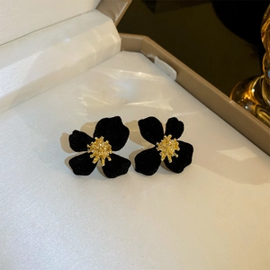 Detailed close-up of a black flocked flower earring with a textured golden core insert