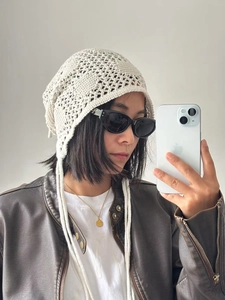Détail du bonnet au crochet crème avec motif ajouré et longues attaches latérales