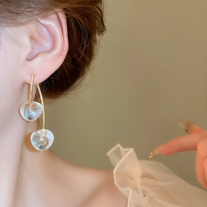 Close-up of dangling cherry-shaped earrings with glass drops on a gold metal hook