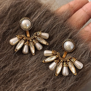 Détail des boucles d'oreilles vintage dorées en forme d'éventail avec perles et cristaux