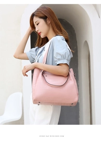 Detail of pink faux crocodile leather tote bag with sturdy handles and protective bottom studs