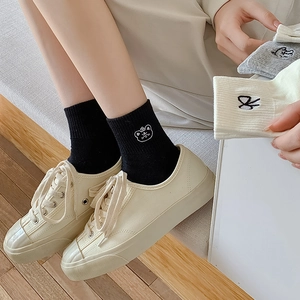 Off-white canvas shoes paired with black bear embroidery knit socks on wooden floor