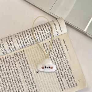 Close-up of a plush white cloud charm with cute embroidery on an open book