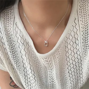 Detail of 925 sterling silver knot pendant necklace worn on a delicate collarbone