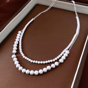 Detailed macro view of double-layered silver pearl necklace with gradient bead design