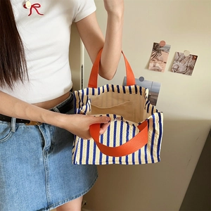 Close-up of blue and yellow striped canvas tote bag with vibrant orange fabric handles