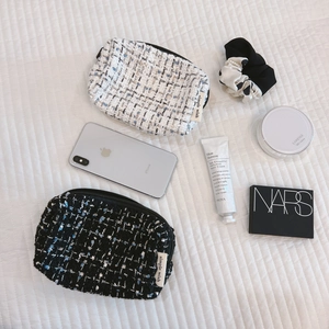 Tweed cosmetic bag in black and white checkers showing makeup and phone storage