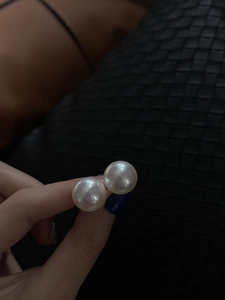Close-up of high-luster white round pearl earring with iridescent glow on 925 silver needle