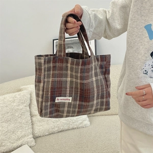 Detailed close-up of the vintage plaid pattern and brand label on a canvas tote bag