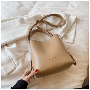 Detail view of khaki leather bucket bag featuring a minimalist logo and sturdy handle