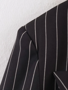 Close-up of shoulder tailoring and stitching on a black striped blazer for women