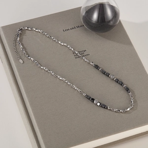 Detailed shot of titanium steel necklace with grey beads on a grey book background