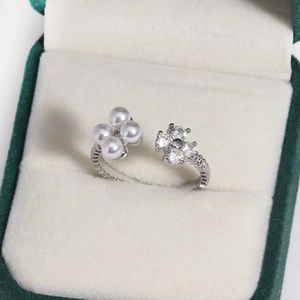 Detail of silver twisted band ring with imitation pearls and a zircon flower on a jewelry box