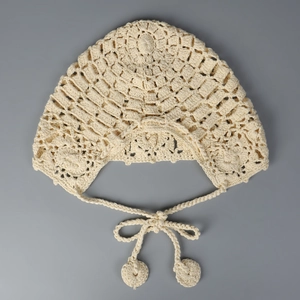 Détail du béguin au crochet pour bébé avec glands fait main en tissu de coton blanc cassé
