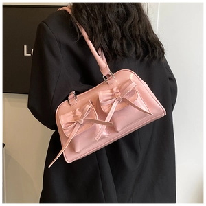Détail du sac bandoulière en cuir verni rose avec nœuds décoratifs et poches à rabat