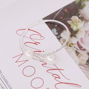 Detail of silver pearl bracelet with sparkling rhinestones and elegant floral background