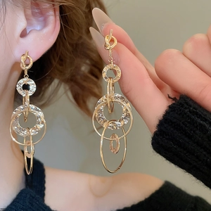 Close-up of golden multi-layered knotted round tassel earrings worn by a model